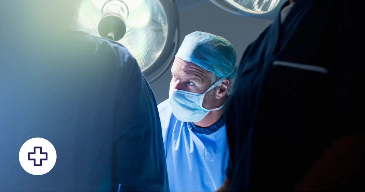 Ein Chirurg ist auf einen Eingriff konzentriert. Er ist umgeben von medizinischen Fachkräften.