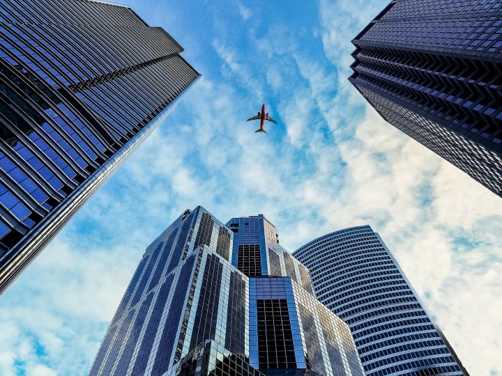Three skyscrapers photographed from below while an airplane is flying across them