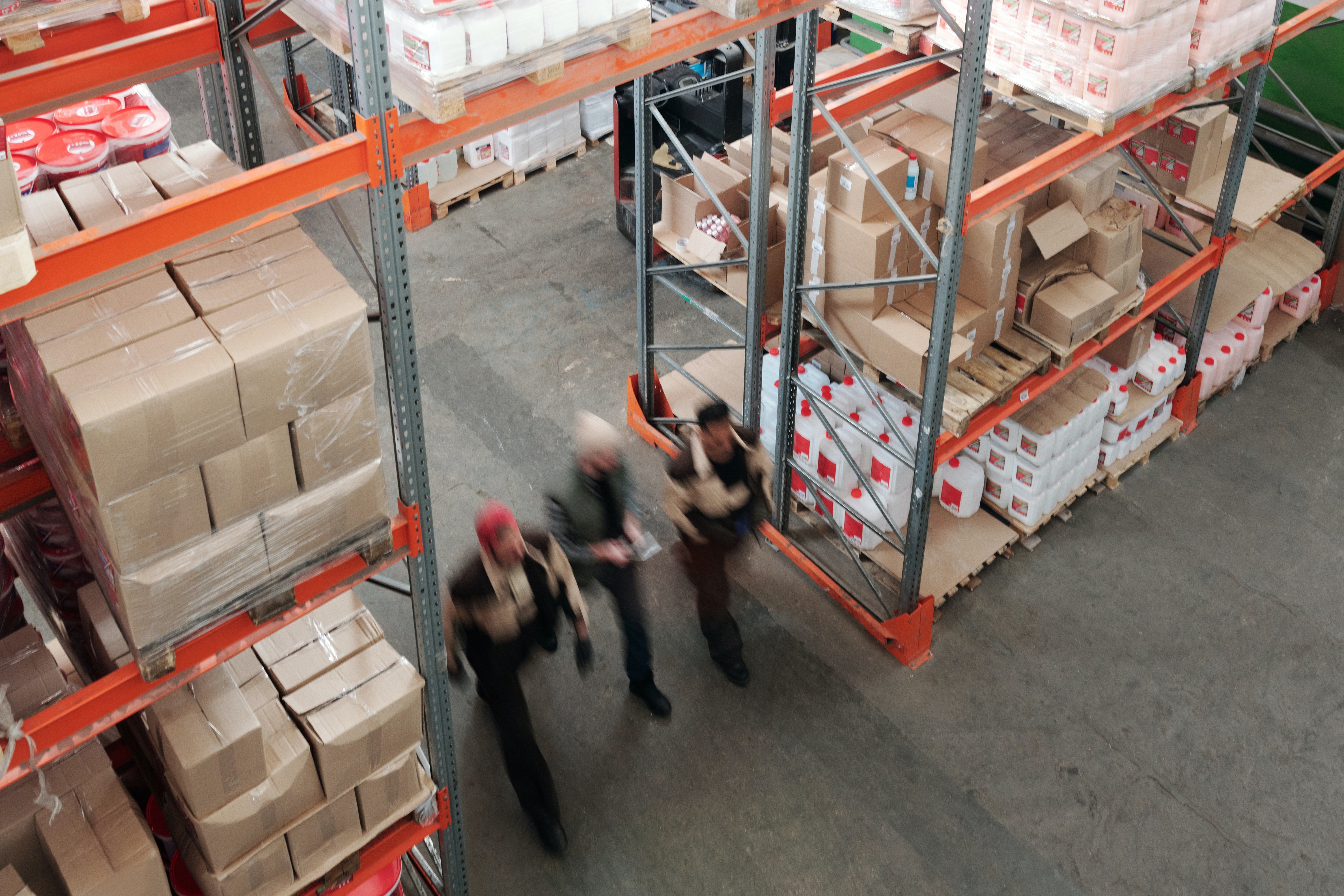 Employees walk past shelves in a warehouse