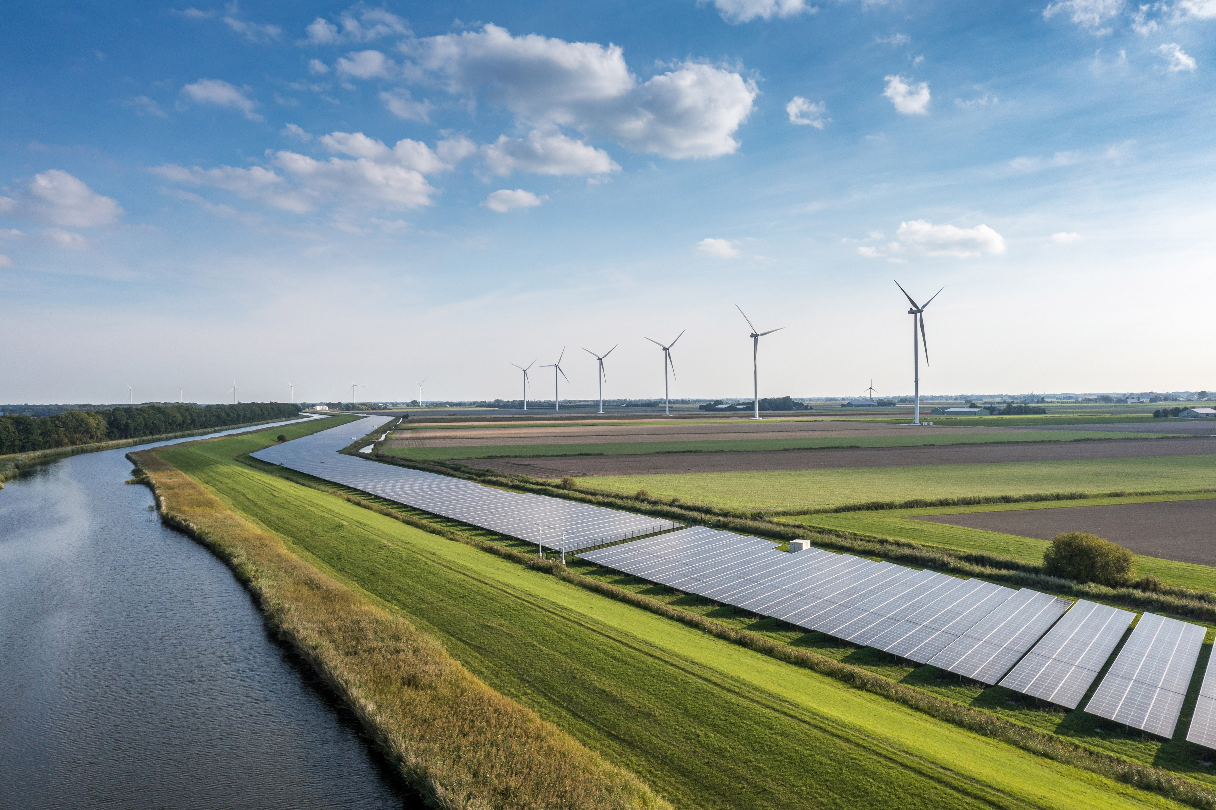 Wind turbines and solar panels by a river