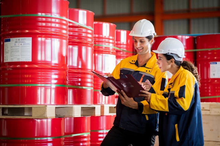 Two factory workers or inventory inspector conduct professional inspection on chemical barrels in warehouse