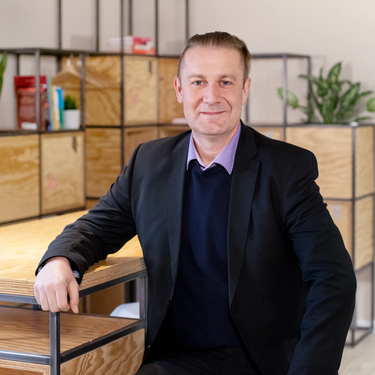 Ein Mann steht an einem Tisch, auf dem sein Arm aufliegt, und schaut zum Fotografen