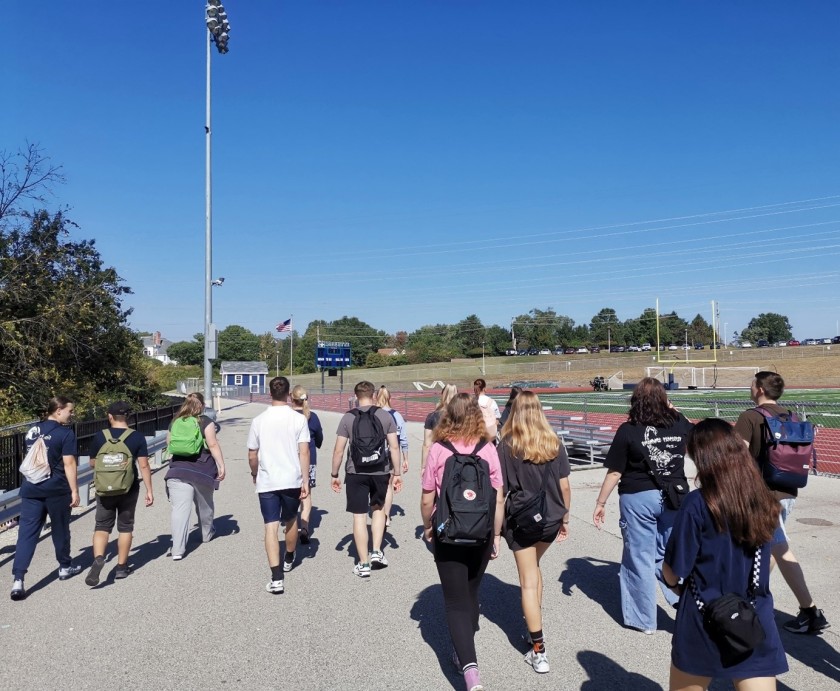 Eine Gruppe Jugendlicher läuft auf dem Sportgelände einer High School herum.