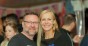 Portrait of a man and a woman with her name tag smiling in the indoor venue Blurred background with more people