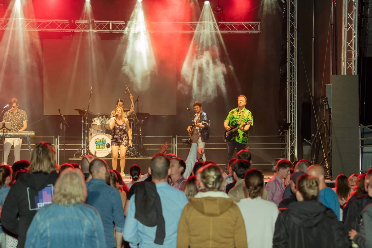 A band playing on stage. People dancing in front of the stage at night