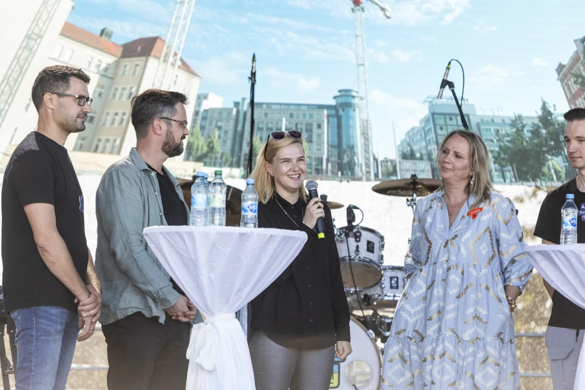 Five people on stage with a Leipzig street view in background