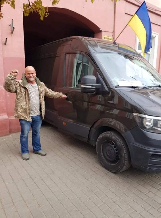A man stands next to a car with Ukrainian flag.