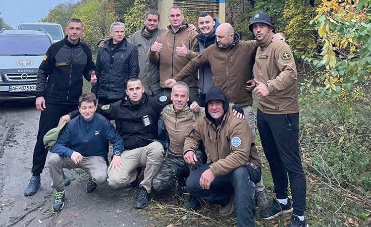 Eine Gruppe von Männern stehen in zwei Reihen, einige von ihnen hocken