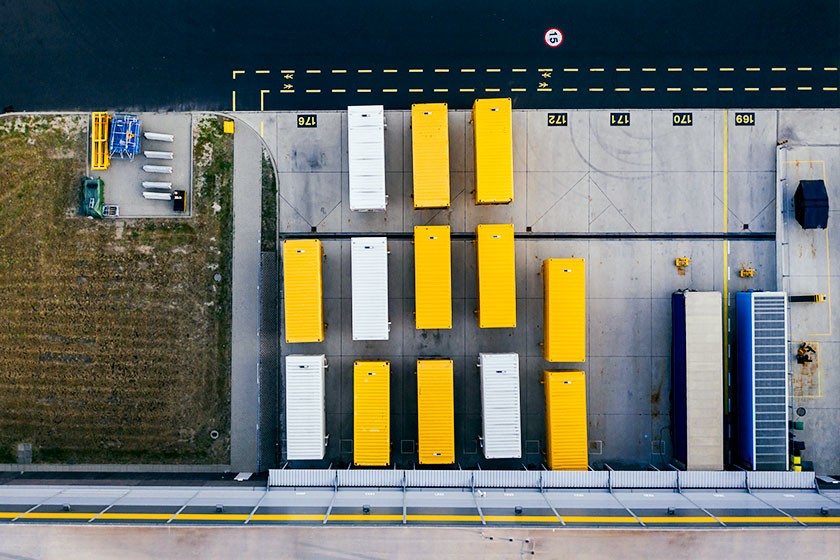 Madártávlatból: tizenhárom sárga és fehér konténer egy raktárterületen.