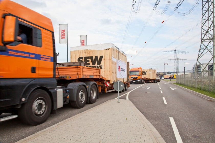 Convoi de deux camions orange avec un chargement SEW-EURODRIVE